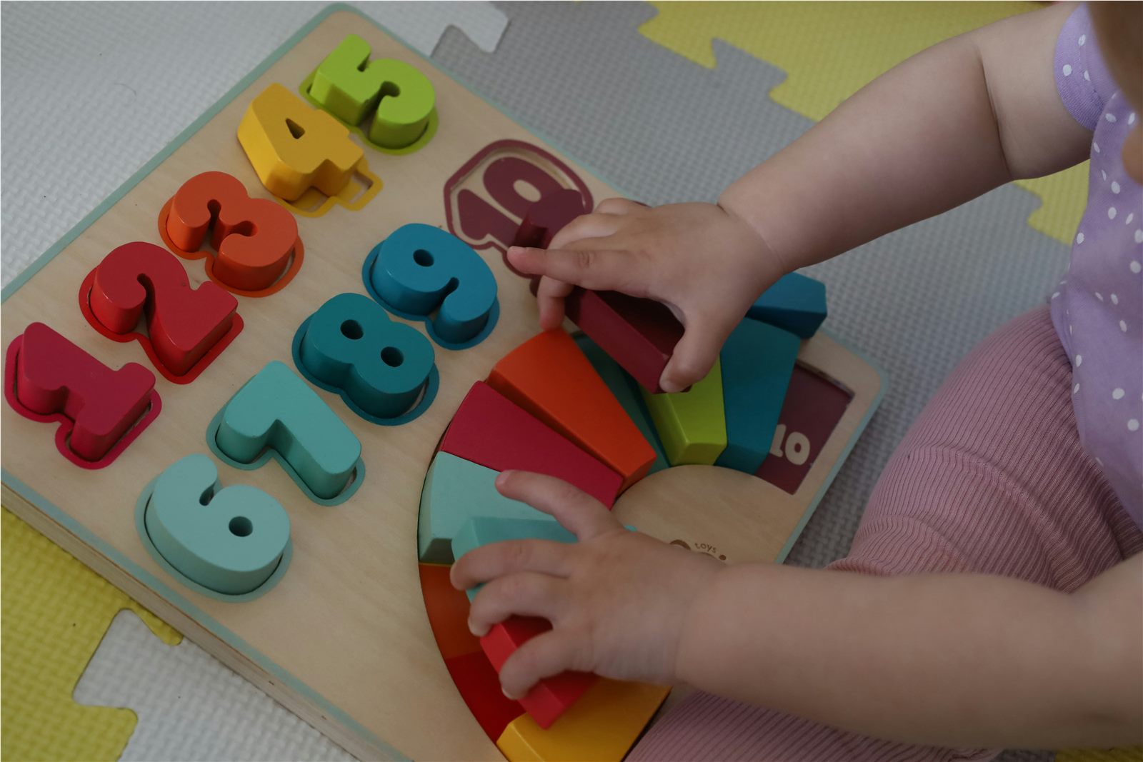 Infant exploring a wooden Montessori number puzzle at BrightSteps in Mississauga